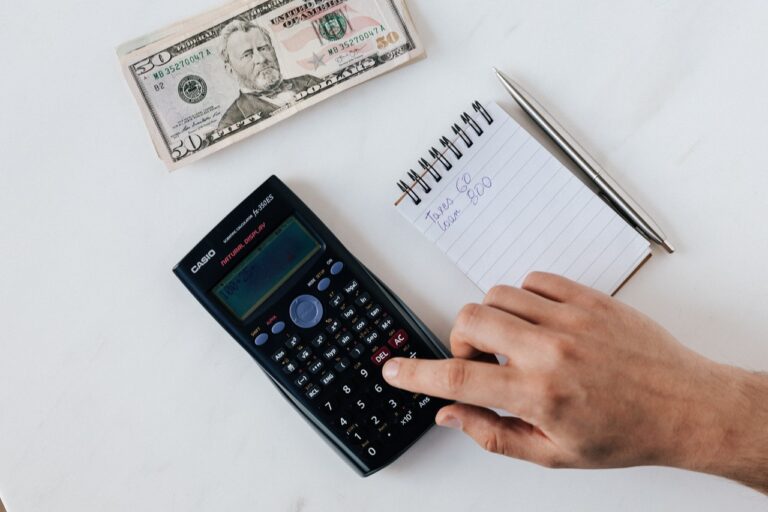 Femme calculant son revenu net à partir d'un salaire brut sur une calculatrice et un ordinateur portable